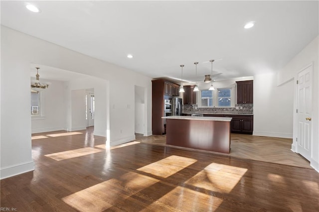 kitchen featuring a center island, sink, hanging light fixtures, decorative backsplash, and dark hardwood / wood-style flooring