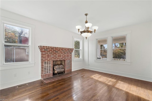 unfurnished living room featuring a notable chandelier, a fireplace, and dark wood-type flooring