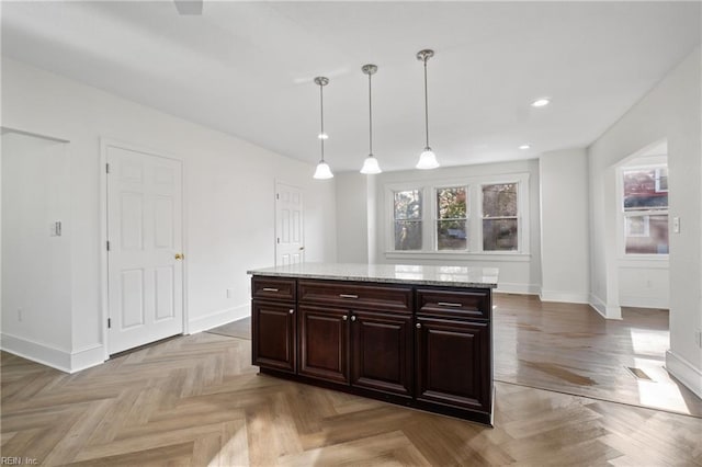 kitchen with pendant lighting, dark brown cabinetry, a wealth of natural light, and light parquet flooring