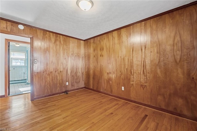 empty room featuring ornamental molding, wooden walls, hardwood / wood-style flooring, and a baseboard heating unit