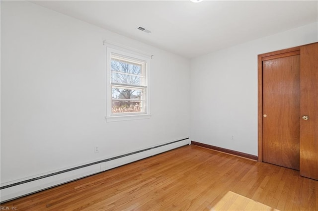 spare room with light wood-type flooring and a baseboard radiator