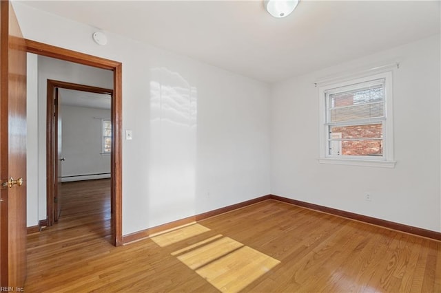 empty room featuring hardwood / wood-style floors, a wealth of natural light, and a baseboard radiator