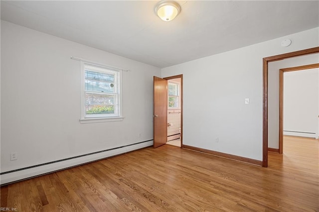 spare room with baseboard heating and light hardwood / wood-style floors