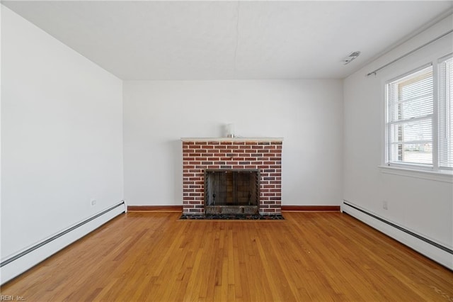 unfurnished living room with wood-type flooring, a brick fireplace, and a baseboard heating unit