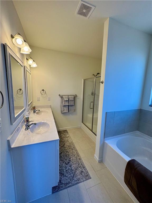 bathroom with tile patterned floors, vanity, and plus walk in shower