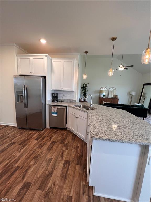 kitchen with dark wood-type flooring, white cabinets, sink, appliances with stainless steel finishes, and decorative light fixtures