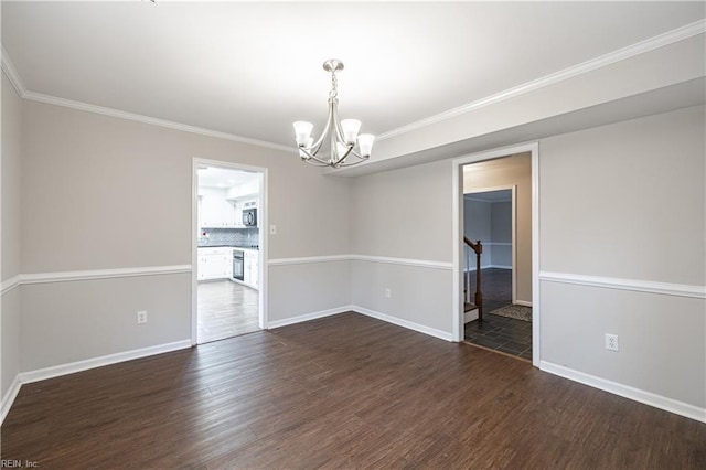spare room featuring a chandelier, ornamental molding, and dark wood-type flooring