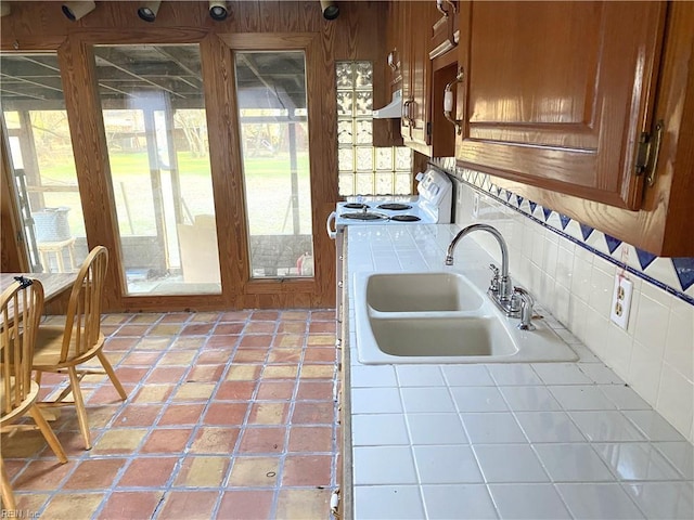 kitchen featuring tile countertops, plenty of natural light, white range with electric stovetop, and sink