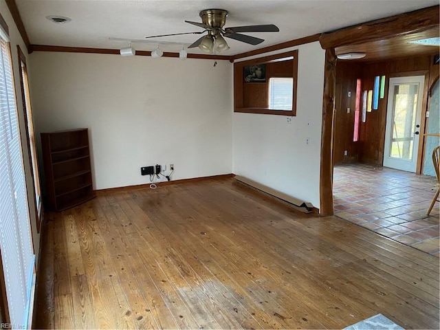 spare room with crown molding, ceiling fan, wooden walls, and wood-type flooring