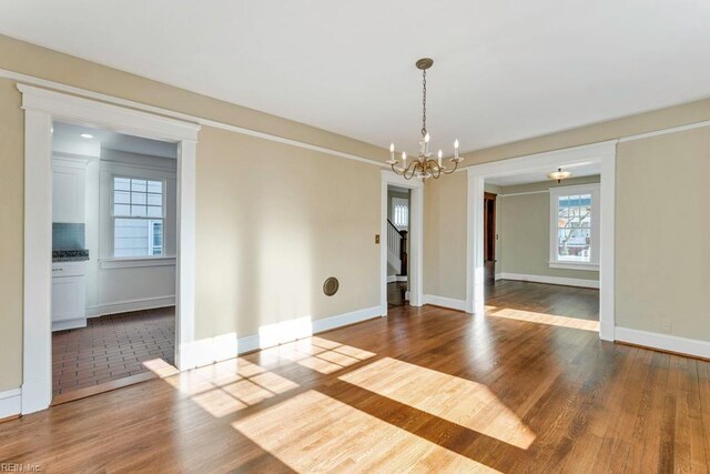 empty room with hardwood / wood-style floors and a chandelier