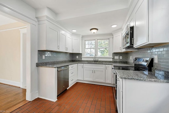 kitchen featuring tasteful backsplash, stainless steel appliances, sink, stone countertops, and white cabinetry