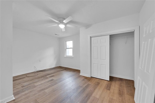 unfurnished bedroom featuring ceiling fan, light hardwood / wood-style floors, and a closet