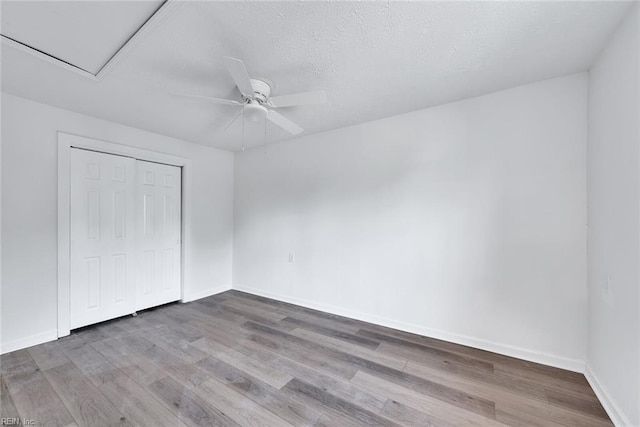 unfurnished bedroom featuring a closet, ceiling fan, hardwood / wood-style floors, and a textured ceiling