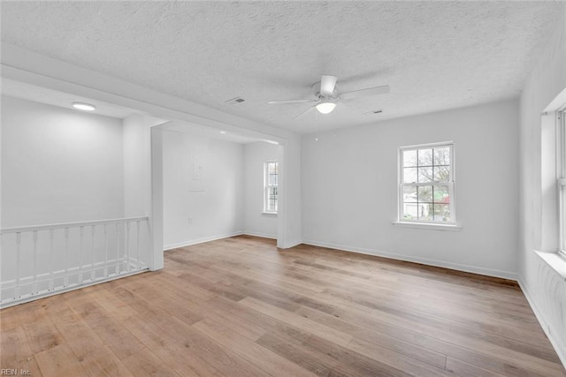 empty room with a textured ceiling, light hardwood / wood-style flooring, and ceiling fan