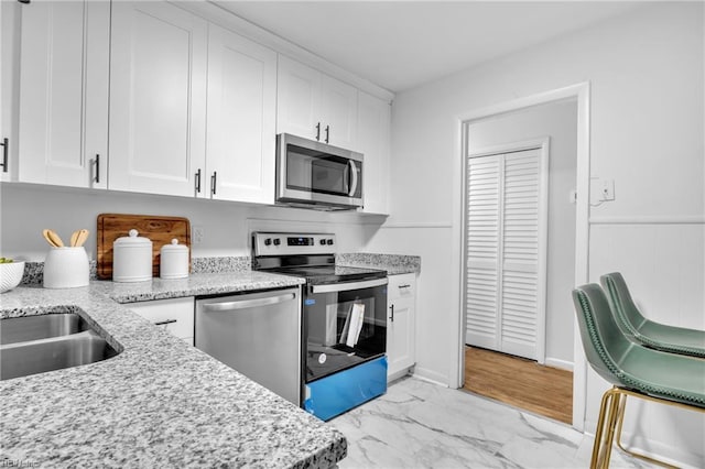 kitchen with white cabinets, appliances with stainless steel finishes, and light stone countertops