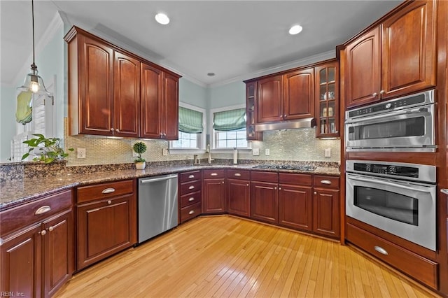 kitchen featuring decorative light fixtures, tasteful backsplash, appliances with stainless steel finishes, and light hardwood / wood-style flooring