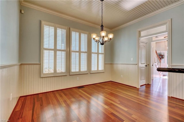 unfurnished dining area featuring hardwood / wood-style floors, an inviting chandelier, and ornamental molding