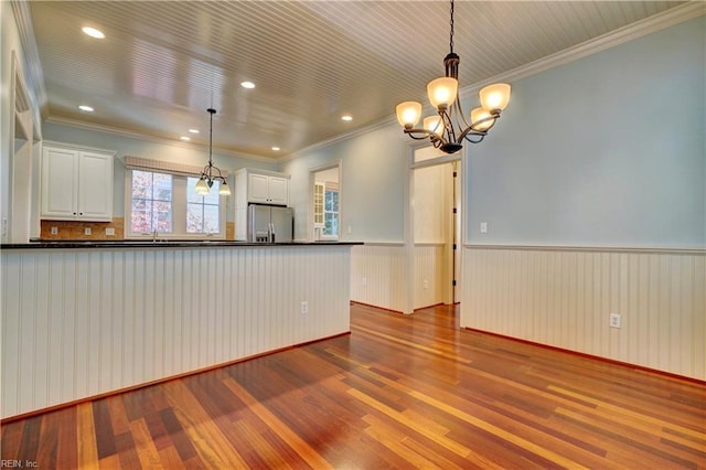 kitchen with white cabinets, hanging light fixtures, stainless steel refrigerator with ice dispenser, and hardwood / wood-style flooring