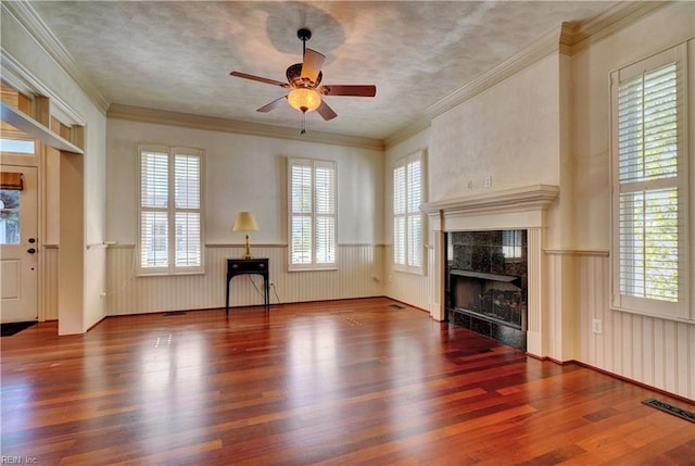 unfurnished living room featuring a textured ceiling, ceiling fan, crown molding, a tile fireplace, and hardwood / wood-style flooring