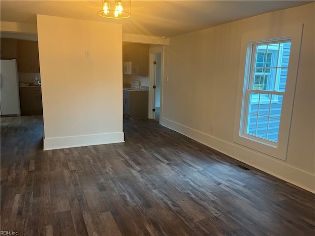 unfurnished living room featuring dark wood-type flooring and a chandelier