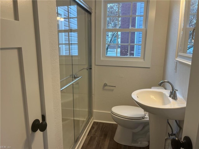 bathroom with sink, hardwood / wood-style floors, a shower with shower door, and toilet