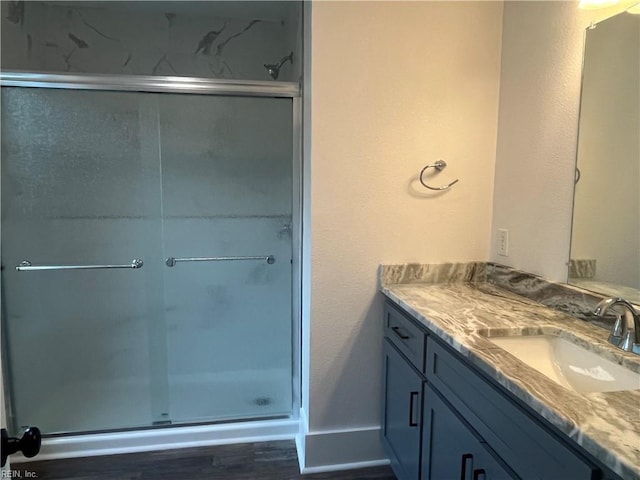 bathroom featuring vanity, a shower with shower door, and wood-type flooring