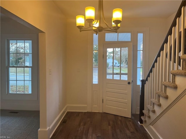 entryway with dark wood-type flooring and a chandelier