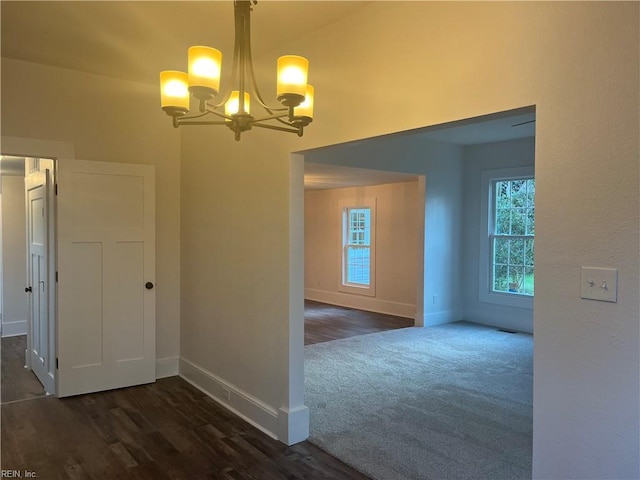 unfurnished room featuring a chandelier and dark hardwood / wood-style floors