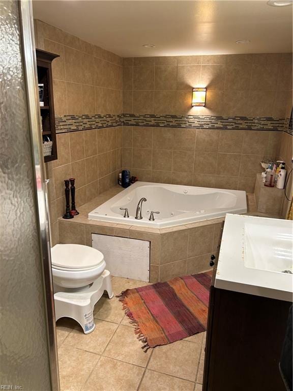 bathroom with vanity, tile walls, tile patterned flooring, tiled bath, and toilet