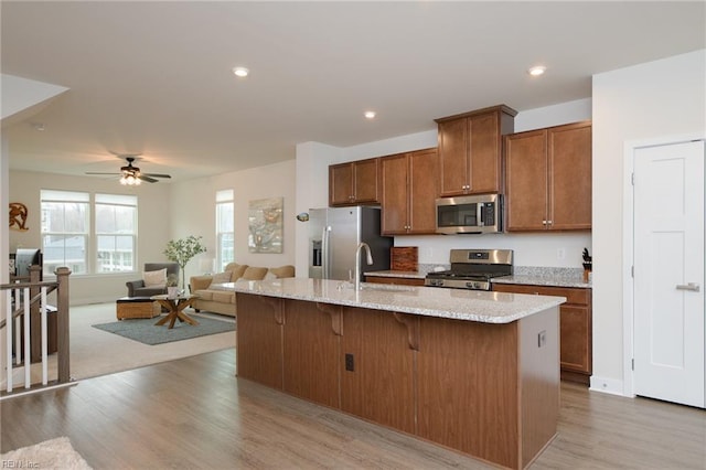 kitchen featuring a kitchen breakfast bar, a kitchen island with sink, light hardwood / wood-style flooring, and stainless steel appliances