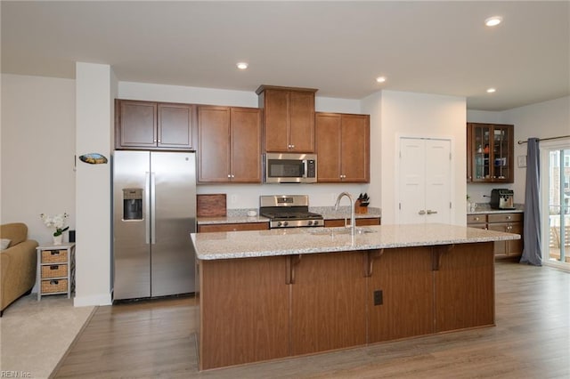 kitchen featuring a center island with sink, sink, light wood-type flooring, a kitchen bar, and stainless steel appliances