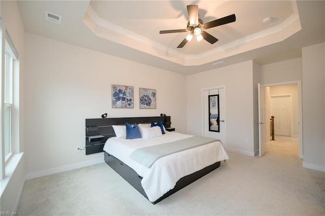 carpeted bedroom featuring ceiling fan and a raised ceiling