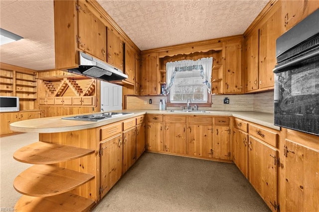 kitchen featuring kitchen peninsula, stainless steel gas cooktop, wooden walls, sink, and black oven