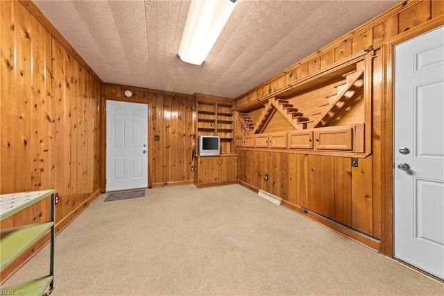 carpeted spare room featuring wood walls