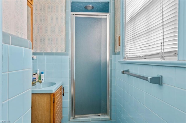 bathroom with vanity, a shower with door, and tile walls