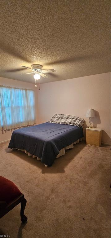 bedroom with carpet, a textured ceiling, and ceiling fan