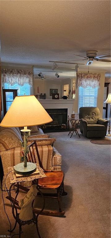 carpeted living room with ceiling fan and a textured ceiling