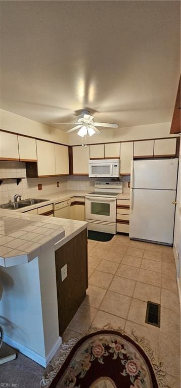 kitchen with tile counters, sink, tasteful backsplash, white appliances, and white cabinets