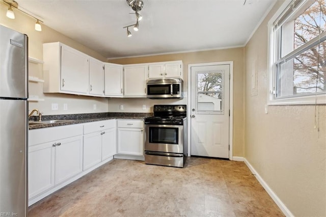 kitchen featuring track lighting, stainless steel appliances, white cabinetry, and sink