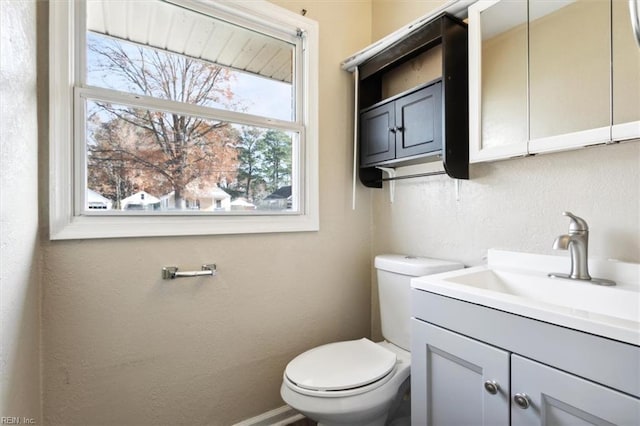 bathroom with a wealth of natural light, vanity, and toilet