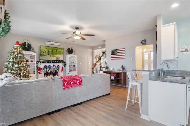 living room featuring ceiling fan, sink, and light hardwood / wood-style flooring