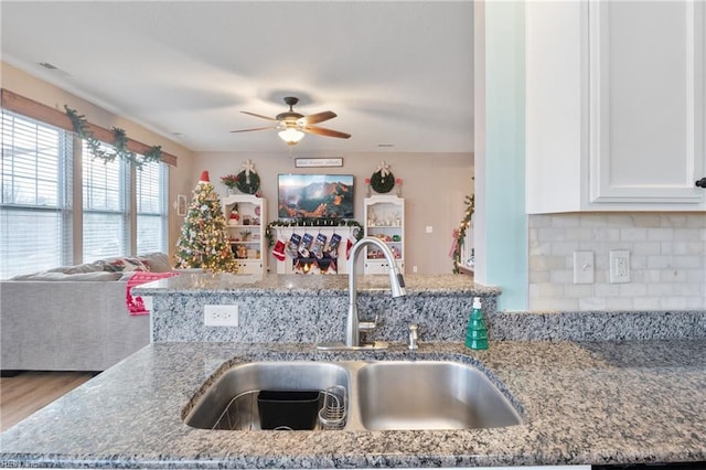 kitchen with backsplash, light stone counters, ceiling fan, sink, and wood-type flooring