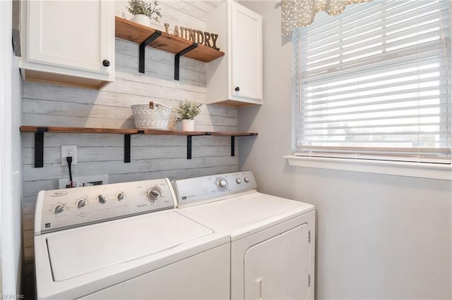 washroom featuring cabinets, an inviting chandelier, wood walls, and washing machine and clothes dryer