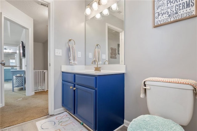 bathroom with a textured ceiling, vanity, and toilet