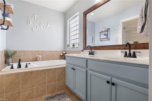 bathroom featuring vanity, a relaxing tiled tub, and tile patterned floors