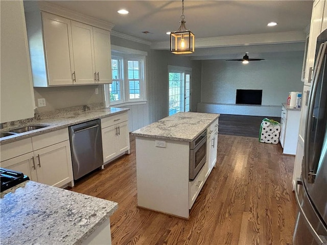 kitchen featuring a center island, dark wood-type flooring, white cabinets, hanging light fixtures, and appliances with stainless steel finishes