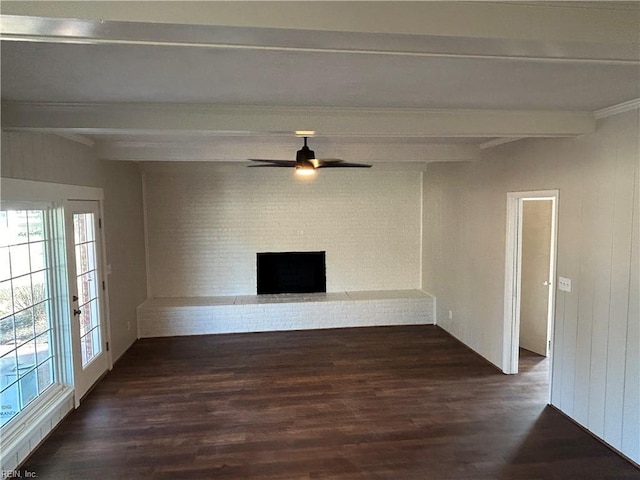 unfurnished living room featuring beam ceiling, ceiling fan, dark wood-type flooring, and a brick fireplace