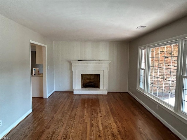 unfurnished living room with dark wood-type flooring and a brick fireplace