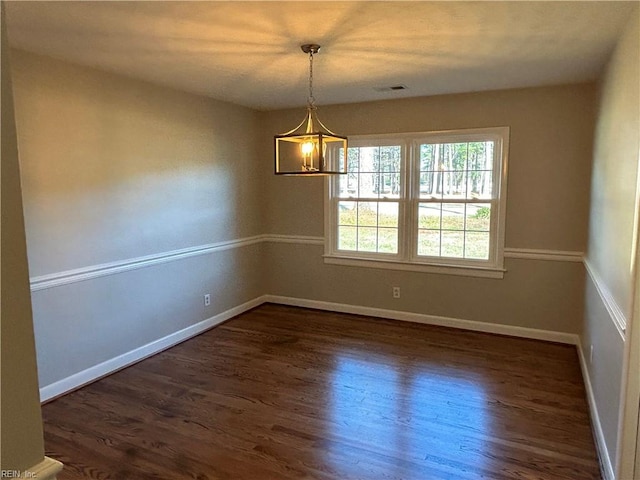 empty room featuring a chandelier and dark wood-type flooring