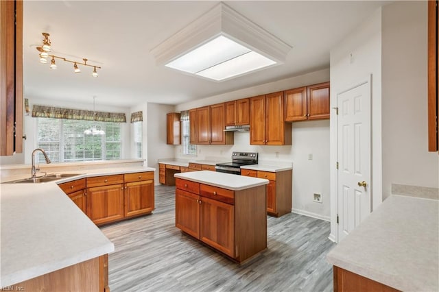 kitchen featuring sink, hanging light fixtures, electric range, light wood-type flooring, and a kitchen island